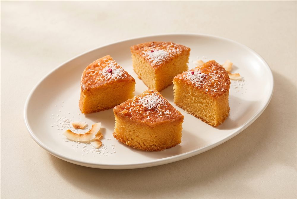 A golden mini coconut cake portion with a delicate coconut finish. Serving presentation.