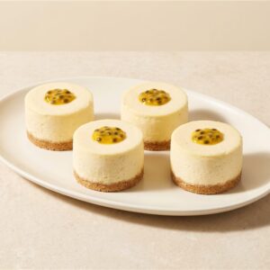 Creamy individual cheesecake with a biscuit crumb base and tangy passionfruit topping. Serving presentation.